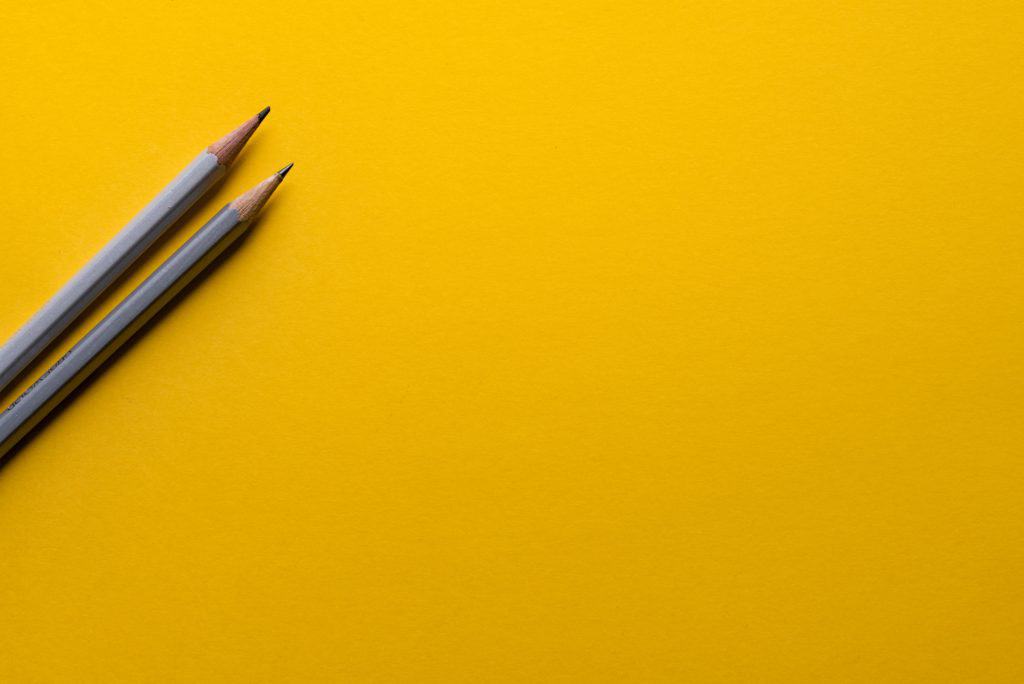 Yellow background with two pencils.